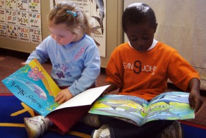 Two toddlers looking at books.