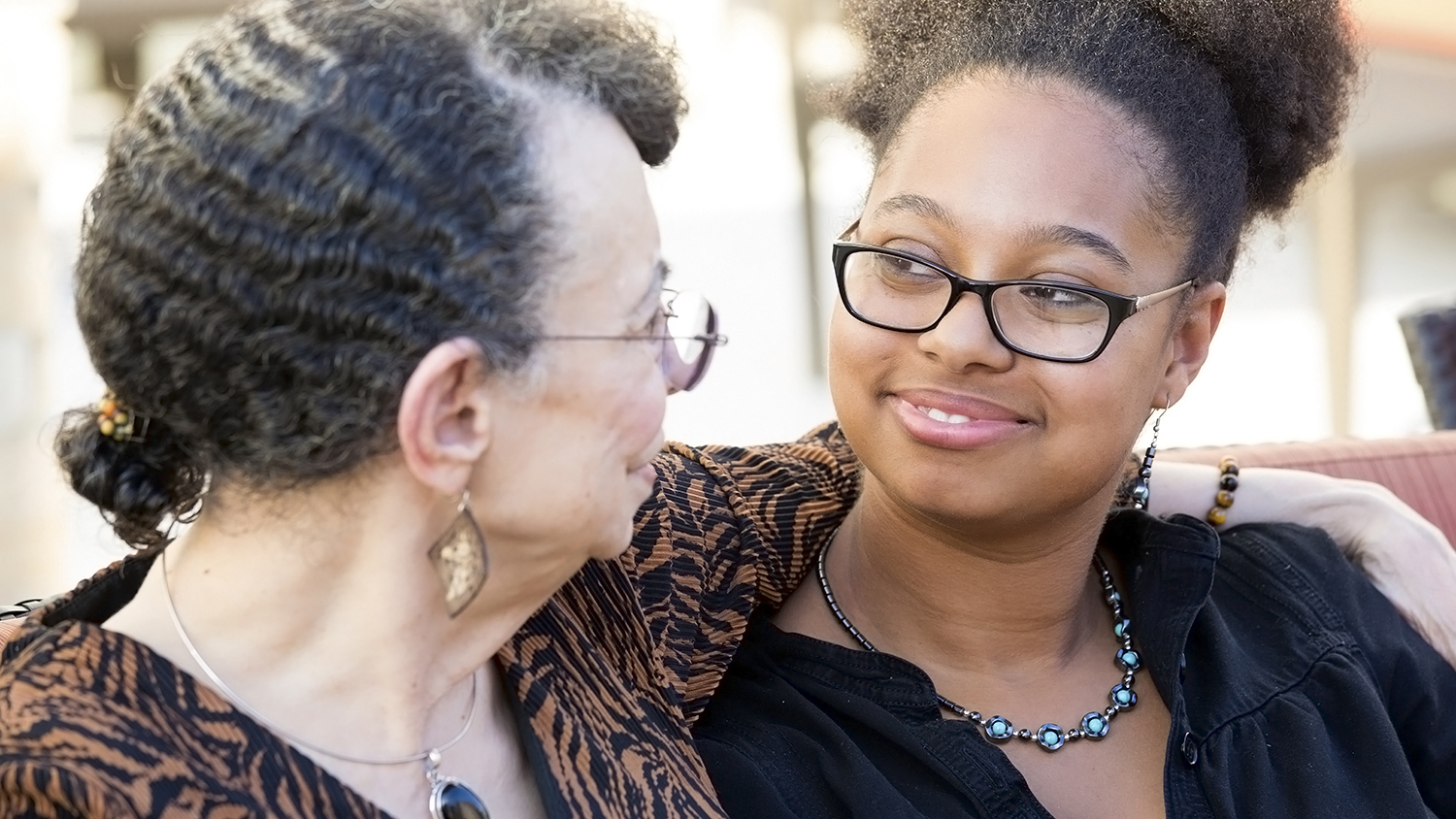 Granddaughter and grandmother sitting, having deep conversation, looking at each other.