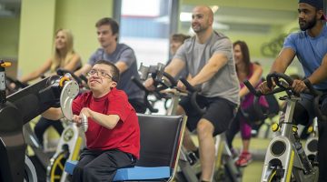A man with a disability is working out at the gym on a cycling machine.