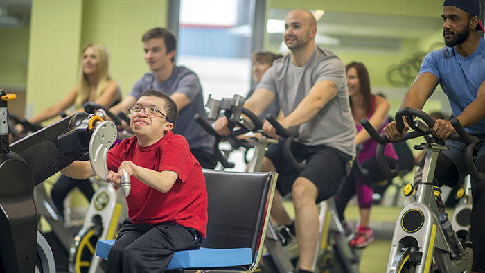 A man with a disability is working out at the gym on a cycling machine.