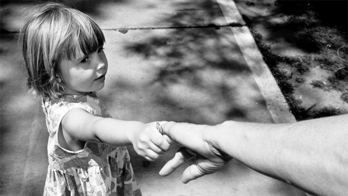 Young girl reaching for an adult's hand.