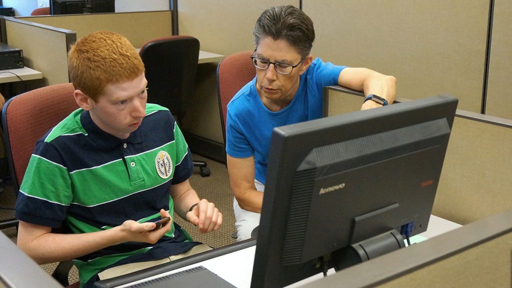 Janet May assisting a student from the Summer Work for ME project to fill out an online form.