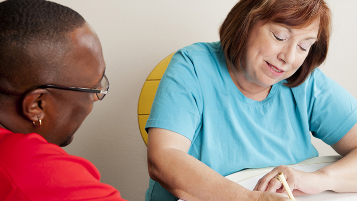 Woman assisting a man with filling out paperwork.