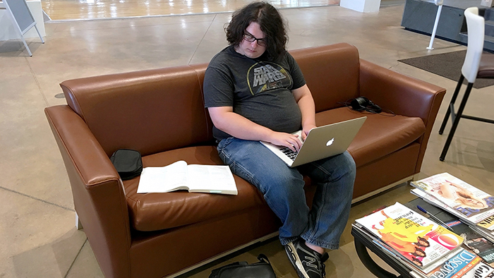 Student seated on a couch studying.
