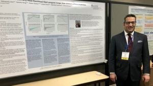 Alan Cobo-Lewis standing in front of his poster at teh 2019 AUCD Conference poster session.