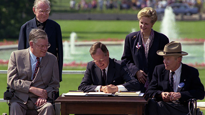 President George H. W. Bush signing the Americans with Disabilities Act of 1990 into law on the South Lawn of the White House (07/26/1990).
