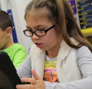 Grade school girl working on her tablet in the classroom.