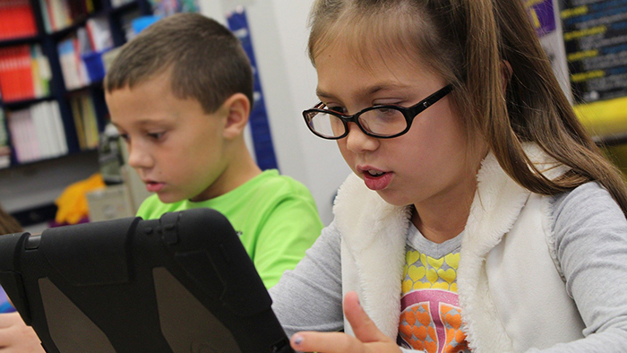 School children using an tablet.