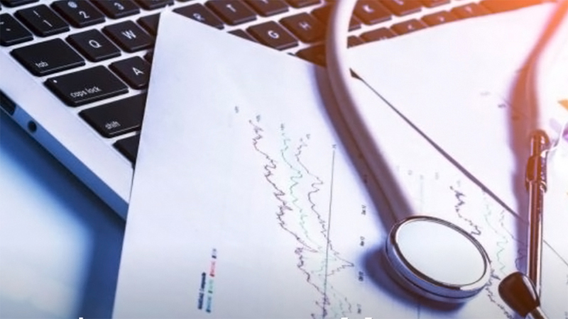 A stethoscope laying on medical papers on a laptop keyboard.