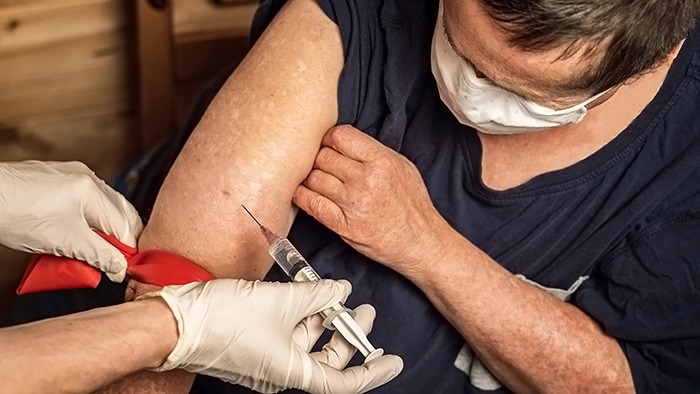 A senior woman with an intellectual disability wearing a blue t-shirt received a COVID-19 vaccination in her home.