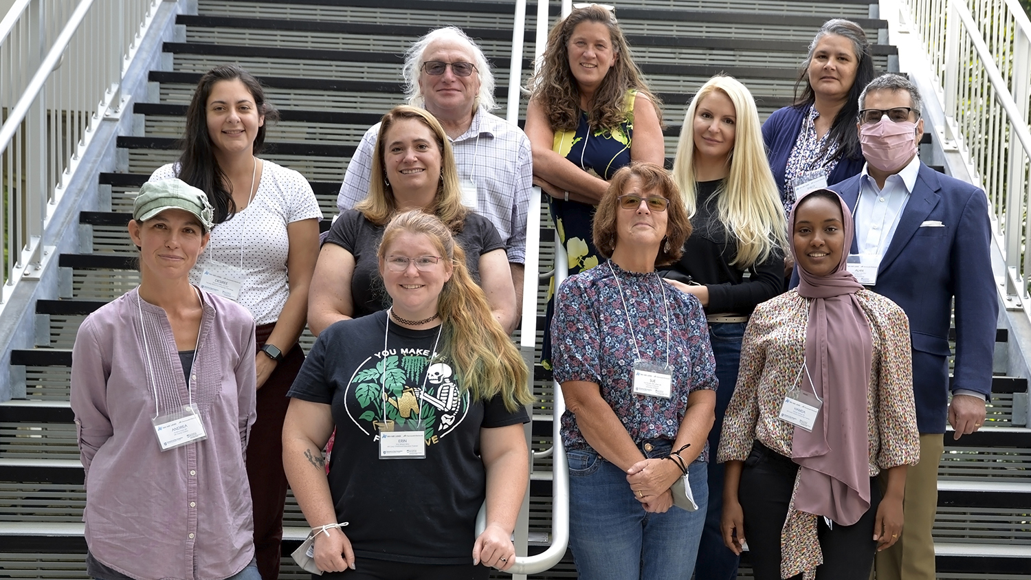 Eleven people (9 women and 2 men) standing outdoors on steps for a group photo.