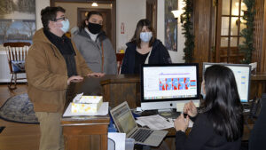 Jake Rousseau, Haily Howard and Christy Rousseau (all masked) standing at the reception desk in the Heritage House.