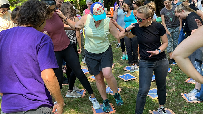 A group of women participating in a team-building exercie in an outdoor setting.