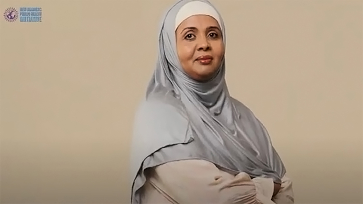A Somali woman wearing a gray traditional head scarf with the New Mainers Public Health Initiative logo in the upper left corner.