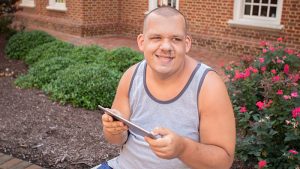 Man with autism using a tablet while sitting outdoors on a bench.
