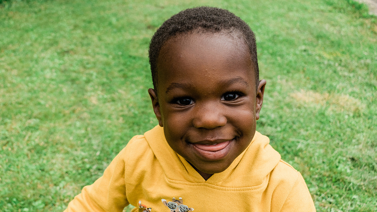 Young Black boy sitting in the grass..